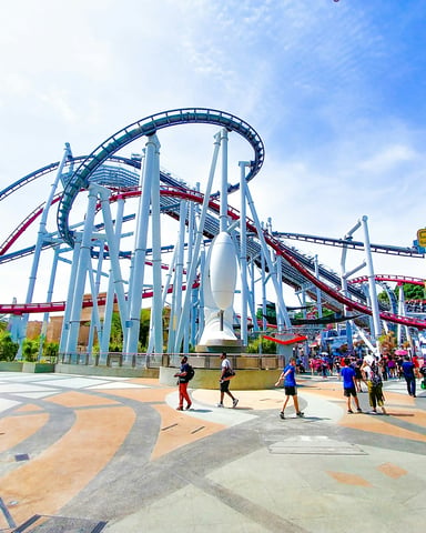 Busy amusement park with roller coasters and families under blue sky