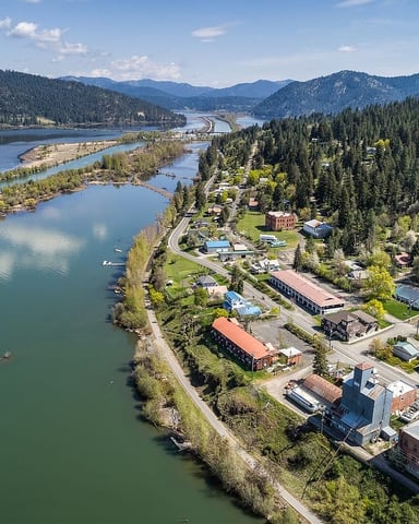 Aerial view of riverside town nestled between forested mountains