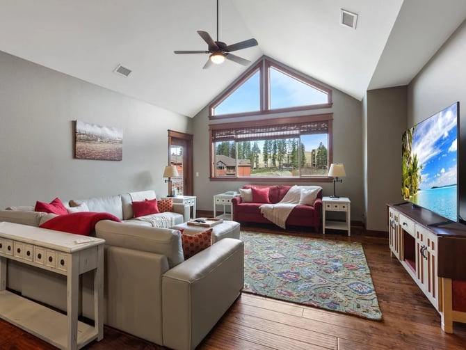 The Bellerose living room with vaulted ceiling, large windows, and seating for a group