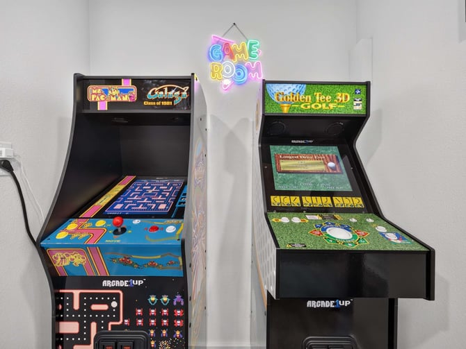 The Clubhouse on 11th game room with two arcade cabinets and a neon Game Room sign